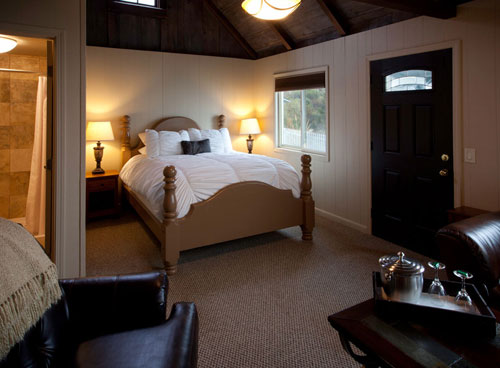 Honeymoon cottage bedroom at Lucia Lodge with four-poster queen bed and black entry door