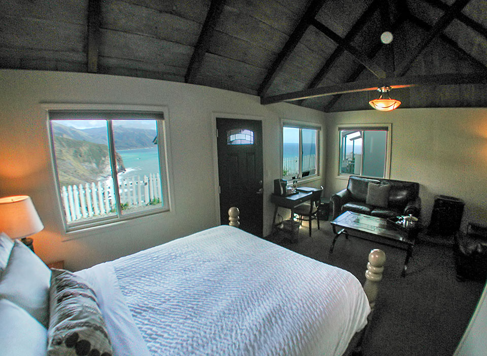 Bed with ocean view window in an Oceanview Luxury cabin at Lucia Lodge