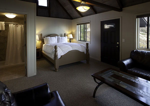 Bed with ocean and mountain view through the window of an Oceanview Luxury cabin at Lucia Lodge